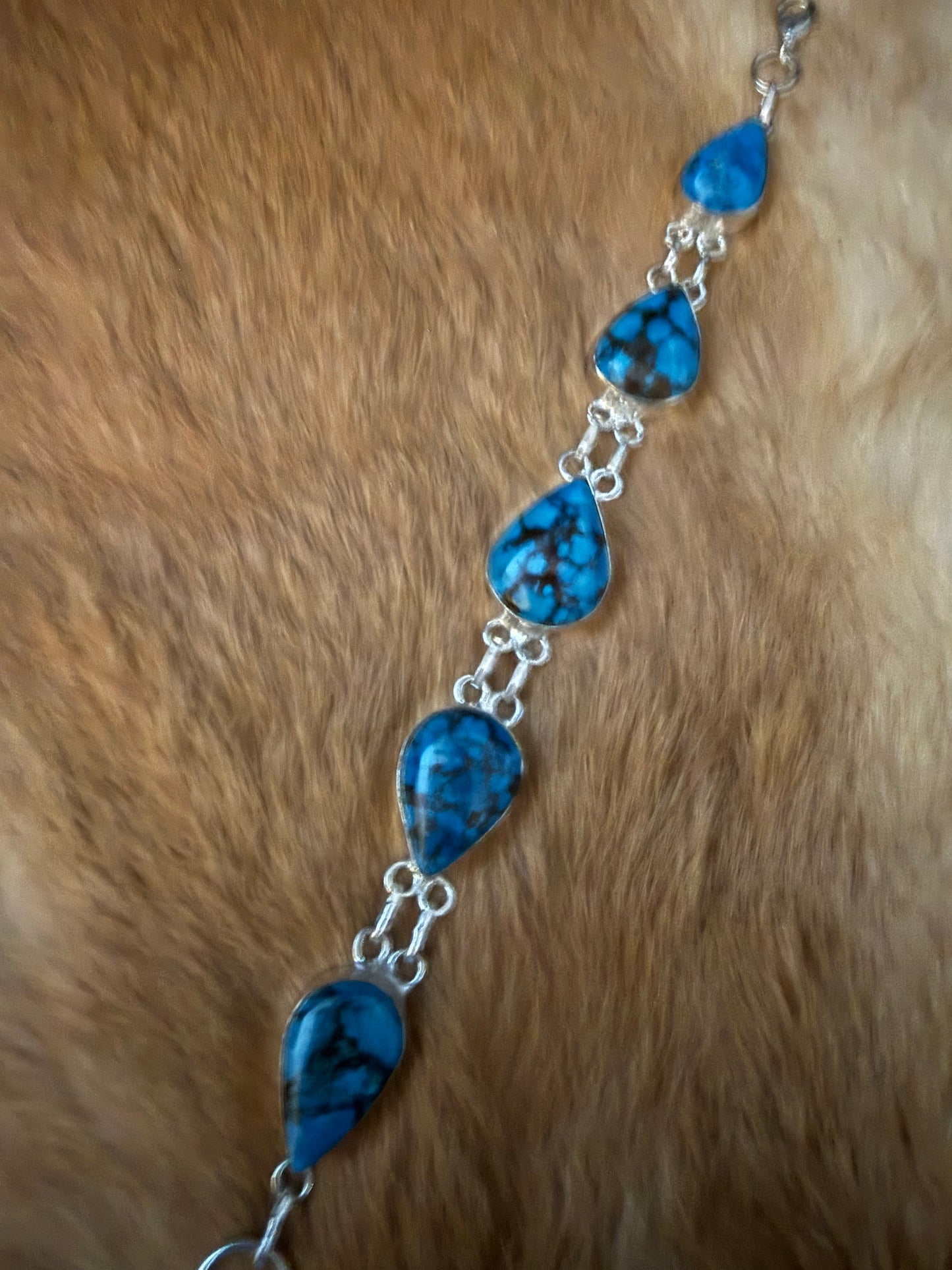 Desert Rain Turquoise Bracelet

Details

* Five teardrop-shaped turquoise stones
* Vivid blue coloring with bold natural matrix
* Sterling silver settings and connecting links
* Each stone is naturally unique

A little piece of the Southwest sky for your